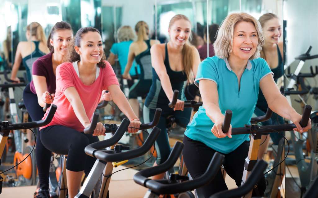 Positive females of different age training on exercise bikes Wallpaper