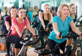 Positive females of different age training on exercise bikes Wallpaper