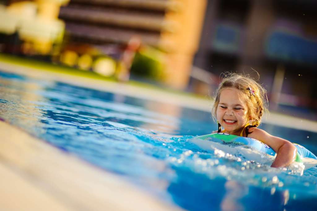 Pretty little girl swimming in outdoor pool and have a fun with inflatable circle