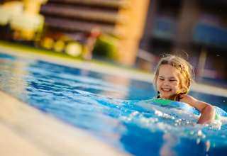 Pretty little girl swimming in outdoor pool and have a fun with inflatable circle