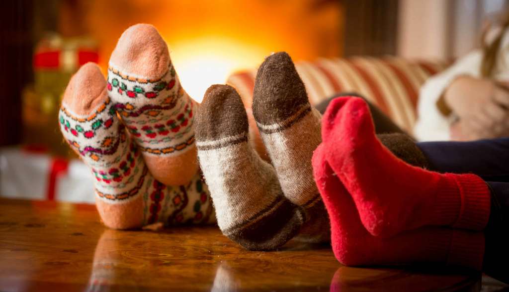 Close-up photo of family feet in wool socks at fireplace