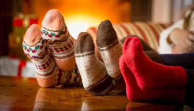 Close-up photo of family feet in wool socks at fireplace