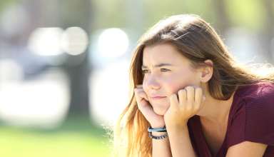 Portrait of angry teen looking sitting alone outside in a park