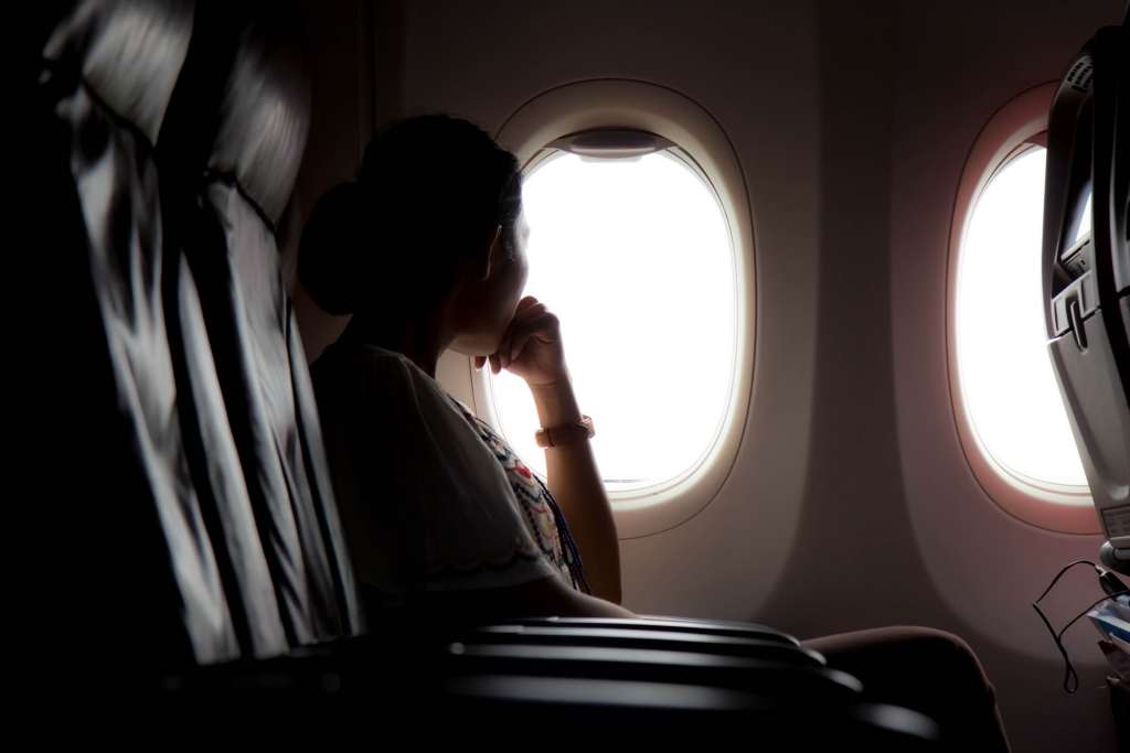 Silhouette of woman looks out the window of an flying airplane