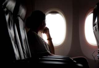 Silhouette of woman looks out the window of an flying airplane