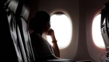 Silhouette of woman looks out the window of an flying airplane