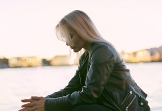 Selective Photography of Woman Sitting Near Body of Water Wallpaper