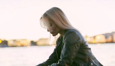 Selective Photography of Woman Sitting Near Body of Water Wallpaper