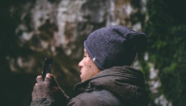 Man Wearing Beanie Holding Smartphone Wallpaper