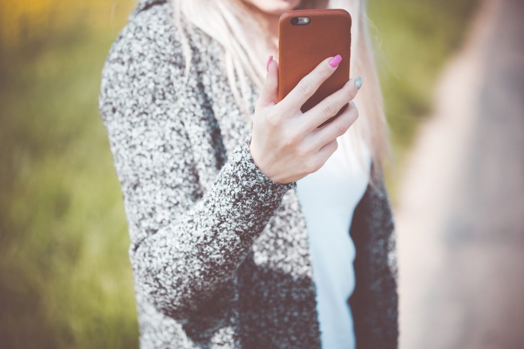 Young Woman Holding Her Iphone in Leather Case Wallpaper