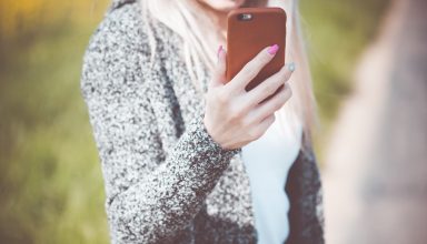 Young Woman Holding Her Iphone in Leather Case Wallpaper